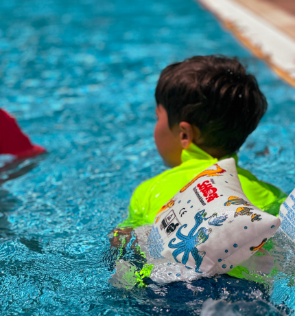 junge im wasser mit schwimmflügeln