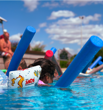 kind schwimmt mit nudel und flügeln